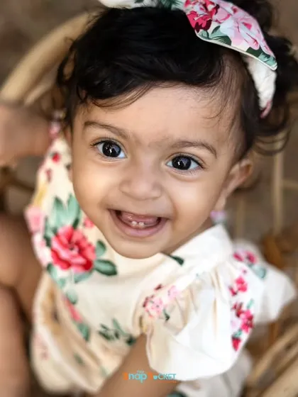 Look at that happy, toothy grin! This close-up shot captures the pure joy of a one-year-old during her outdoor birthday photoshoot.