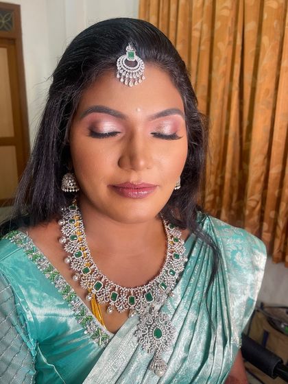 A close-up of my bride Karthiga's reception makeup with her eyes closed. The look features a beautiful pink and silver shimmery eyeshadow, perfect for her sea-green saree.