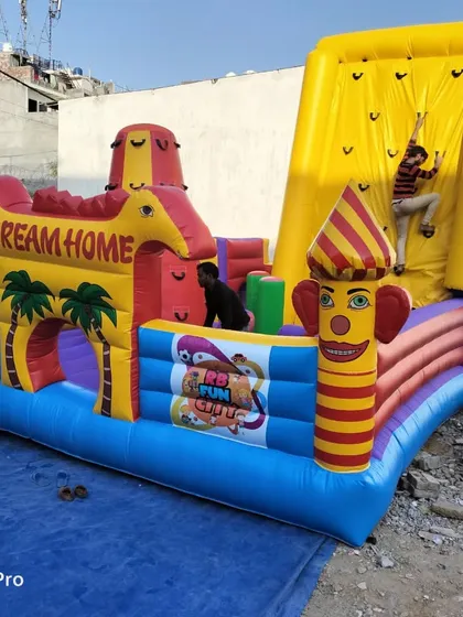 This 20x20 feet combo bouncy castle features a 'Dream Home' theme with an attached tall, yellow climbing wall. It's a great example of how we combine different play elements into one inflatable.