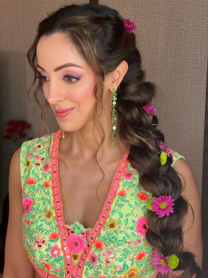 This bride's Mehendi look is completed with a playful and colorful floral braid, a perfect match for her embroidered lehenga.
