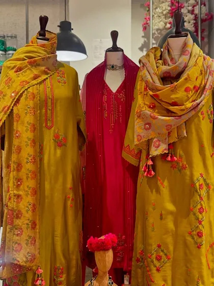 A festive trio in mustard yellow and deep pink. The printed floral dupattas with tassel details add a playful and vibrant touch to these elegant suits.