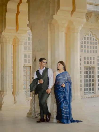 A stylish pose against a palace pillar. This shot showcases the couple's modern attire against the timeless backdrop of classic Rajasthani architecture.