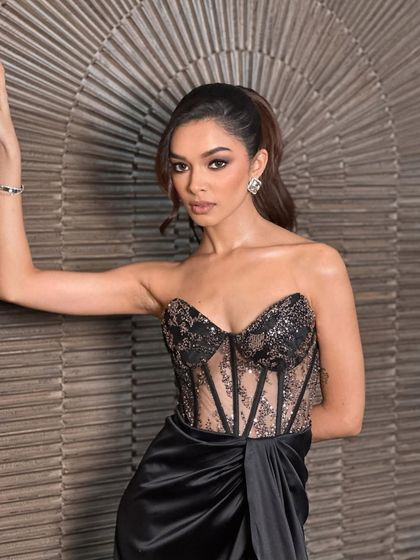 This isn't a look, it's a shutdown. A full-length shot of the model in a black corset gown, with makeup that is all about drama, confidence, and owning the room.
