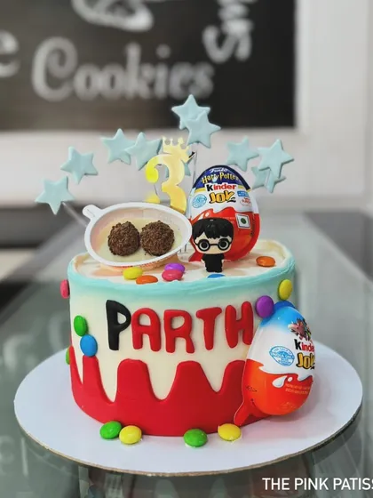 A fun and colorful cake topped with Kinder Joy eggs and a Harry Potter figure. It's a delightful mix of popular treats and characters for a child's birthday.