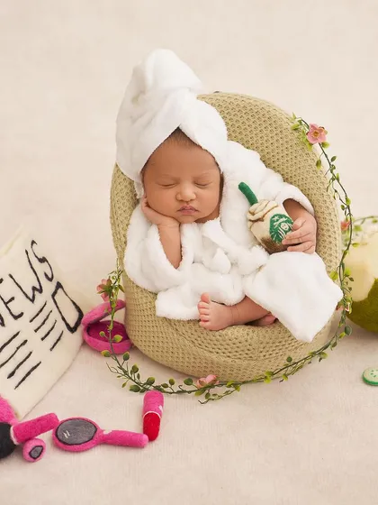 This relaxed newborn enjoys a post-spa nap with a felt newspaper, a tiny hair dryer, and a coconut drink prop.