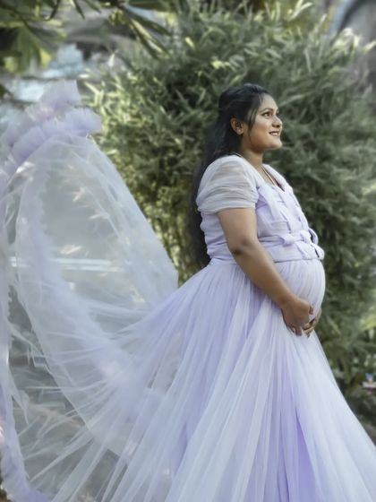 A graceful solo portrait capturing the movement of a light purple gown in the wind. This outdoor shot has a dreamy, ethereal quality, perfect for celebrating motherhood.