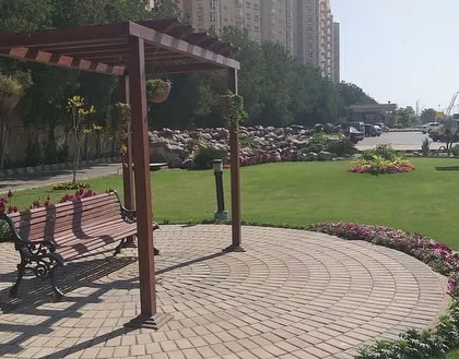 This public park seating area shows how we combine function and beauty. We installed a durable paved circle with a comfortable bench under a wooden pergola, surrounded by a well-maintained lawn and colorful flowerbeds. It’s a perfect example of creating a small, peaceful retreat within a larger green space.