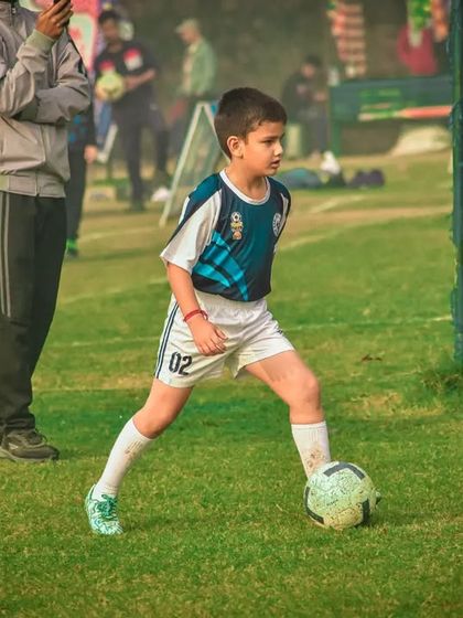 A young player maintains his balance while controlling the ball.