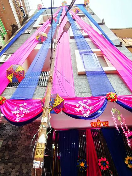 A striking combination of pink and blue drapes for a unique and modern wedding house exterior, accented with traditional umbrellas.