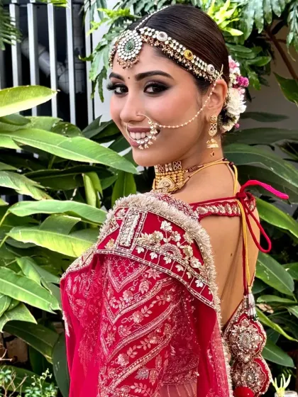 A model showcasing a traditional bridal look with a floral bun. The hairstyle is pulled back neatly, emphasizing the bride's features and jewellery.
