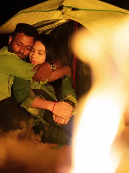 An embrace filled with warmth and affection, seen through the dancing flames of the bonfire. The fire creates a soft, romantic glow, making the moment feel even more intimate.