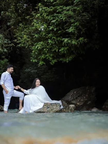 A beautifully composed shot in a river canyon, with the groom leading the bride over the rocks.