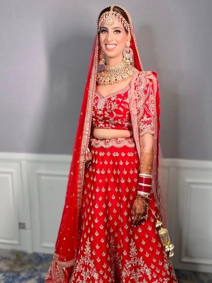 This bride looks radiant and happy in her classic red lehenga. The makeup is bright and fresh, perfect for a day wedding.