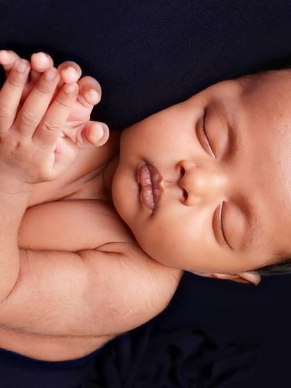 A peaceful and serene portrait, focusing on the baby's face and tiny clasped hands.