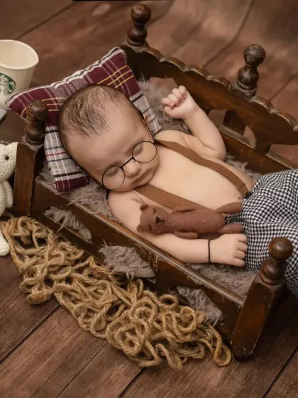 This little guy is sleeping soundly in his miniature bed, surrounded by fun props like a tiny laptop and a coffee cup.