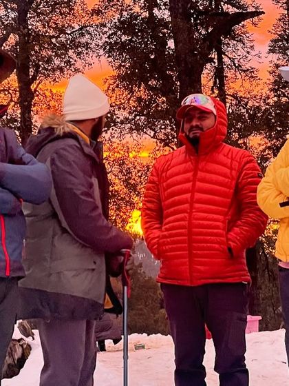 A candid moment of our trek leads and participants sharing a laugh at the Kedarkantha campsite against a beautiful sunset.