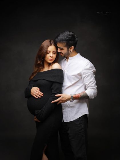 An intimate and stylish portrait in a simple black dress. The focus is on the couple's connection, with the husband's arm gently wrapped around his wife.