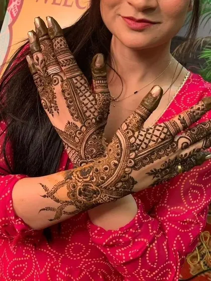 A happy client showing off her full-hand mehendi. The design features a mix of floral, paisley, and geometric elements.