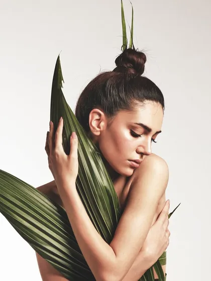 A softer moment from the leaf dress shoot. The focus is on the dewy skin and the way the natural leaves frame the face and body.