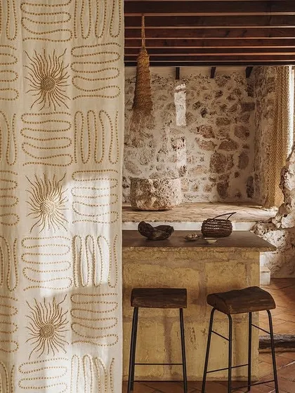 Our Paloma fabric collection, shown here as a curtain, radiates sophistication with its embroidered wooden beads and intricate motifs. This 'Perpétuel Soleil' design is perfect for creating dramatic and artistic window treatments.