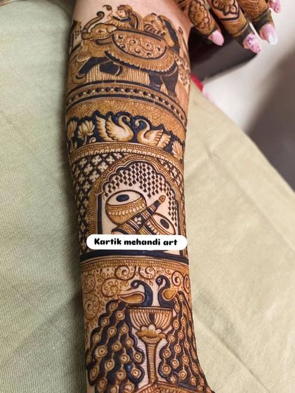A close-up of a forearm band featuring a dhol and an elephant procession. These traditional motifs are perfect for adding a celebratory touch to your bridal mehandi.
