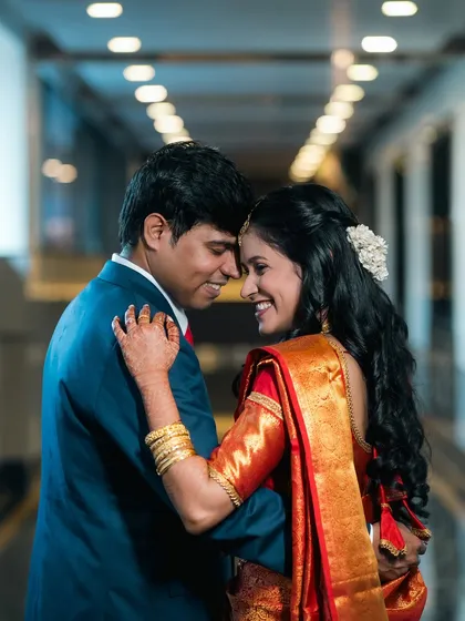 A romantic close-up of a couple, touching foreheads in a brightly lit hallway.