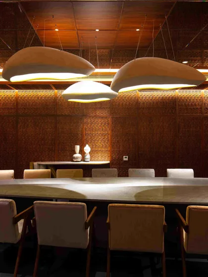 The basement dining room at the Bammi Residence, a space transformed into a jewel box. It features Pinjirakari lattice work, a custom dining table, and lights by Design ni Dukaan to create a warm, intimate atmosphere.