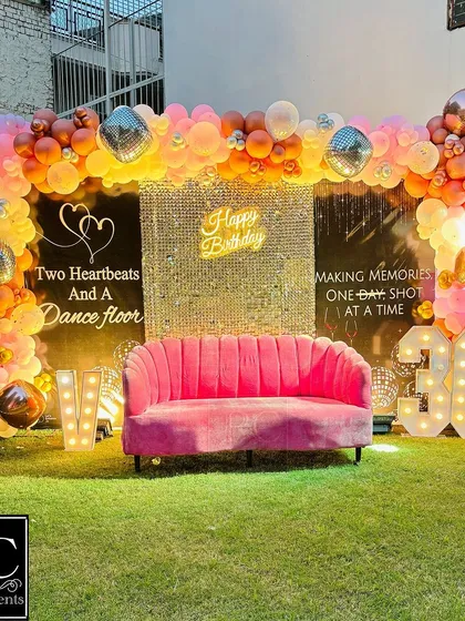 Celebrating a 36th birthday in style with this glamorous outdoor setup. It features a stunning golden sequin wall, a custom neon sign, marquee numbers, and a lush balloon arch, all centered around a chic pink sofa for the perfect photo opportunity.