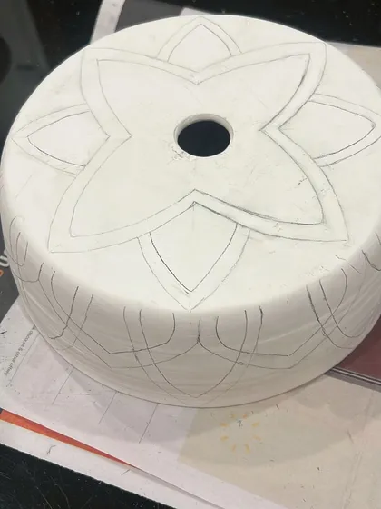 The journey of a lampshade begins with a pencil sketch on greenware (unfired clay). This is where the design is carefully planned before any carving or color is added.