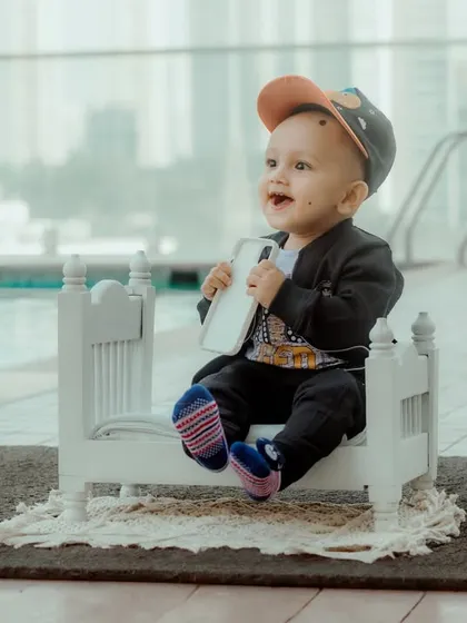 A candid photo of a baby boy looking off to the side with a happy expression, taken during his poolside milestone session.