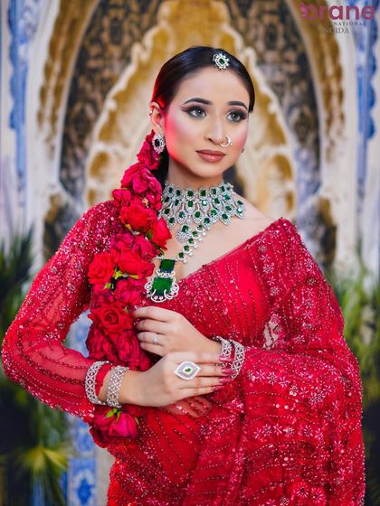 This shot highlights the complete look, including the elaborate jewelry and the sleek, traditional hairstyle adorned with fresh roses.