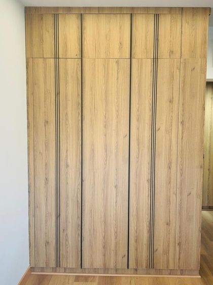 A wardrobe featuring a natural wood finish with sleek, black profile handles that run the full length of the doors. This detail adds a modern touch to the classic wood texture.