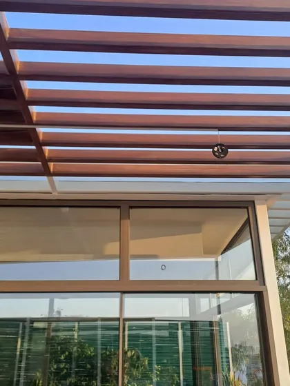 A detailed view of the wooden pergola structure built over a glass roof. This design element adds architectural character while providing partial shade, creating a comfortable and visually interesting environment.