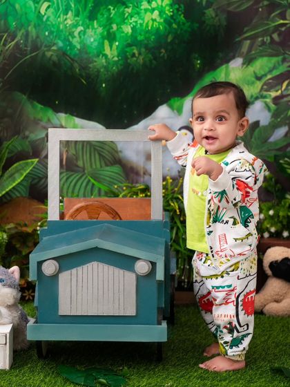 A little explorer ready for a jungle adventure. The jeep prop and dinosaur-print outfit are perfect for a wild and fun photoshoot.