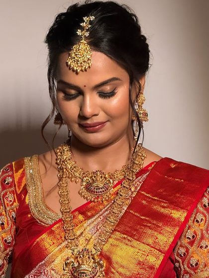 A close-up of a South Indian bride, her eyes lowered, showcasing her beautiful temple necklace and jhumkas.