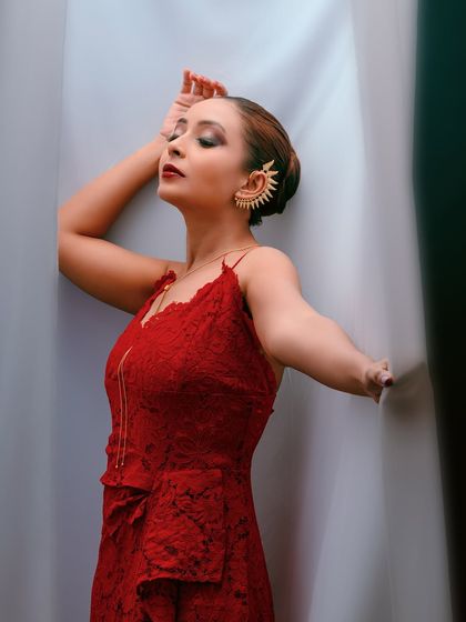 A wider shot that shows more of the red dress and the creative use of the curtains as a prop.