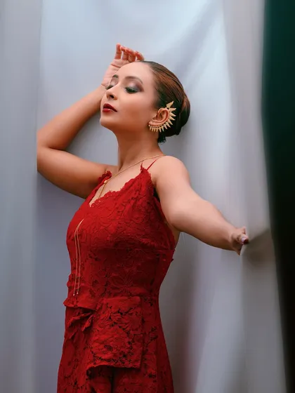 A wider shot that shows more of the red dress and the creative use of the curtains as a prop.