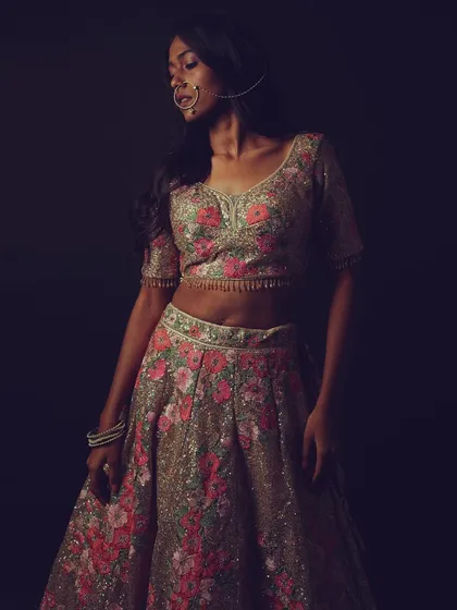 The model wears a beautiful floral embroidered lehenga. The makeup is kept natural to complement the intricate outfit, and a traditional nath adds a bridal touch.