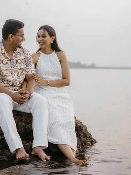 A quiet, shared moment as the couple sits on a rock by the lake, their feet touching the water.