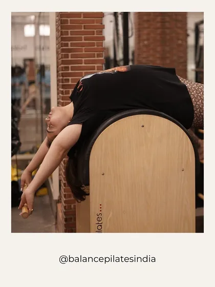 That post-stretch feeling! A client enjoys a deep backbend over the Pilates barrel, a piece of equipment we use for spinal mobility and core work.