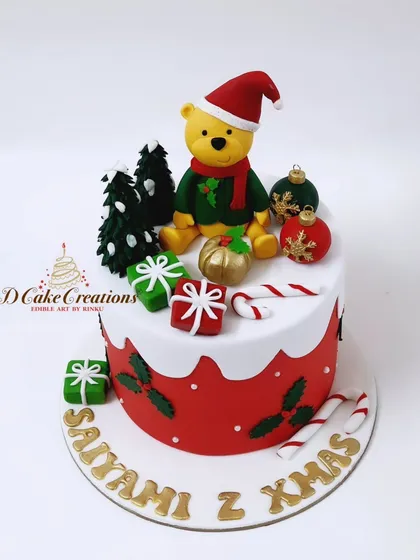 A cute Christmas-themed cake with a festive Winnie the Pooh, edible presents, and candy canes.