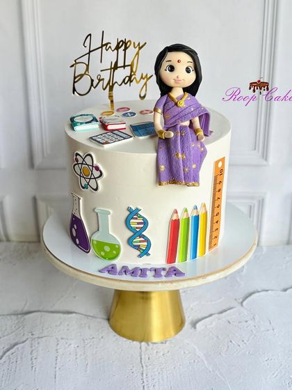 A cake celebrating a passionate science teacher. The design includes a custom fondant figure in a saree, surrounded by edible science-themed decorations like beakers, atoms, and DNA strands.