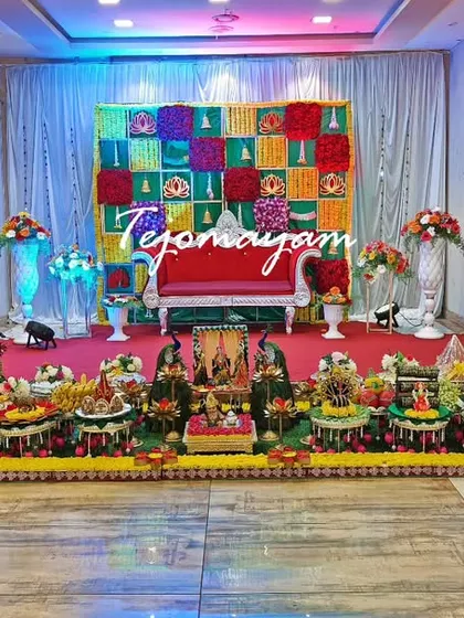 A vibrant baby shower setup with a multi-colored checkered backdrop. The plate decoration is arranged on a red-carpeted stage.