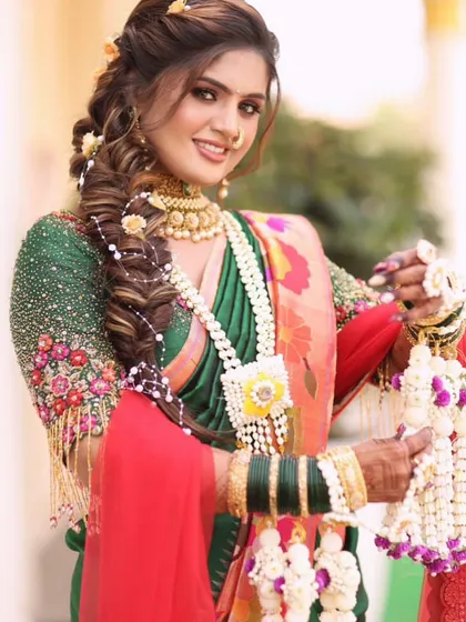 A close-up of a bride's smile and her beautiful floral jewellery, including a necklace and braided hair flowers.