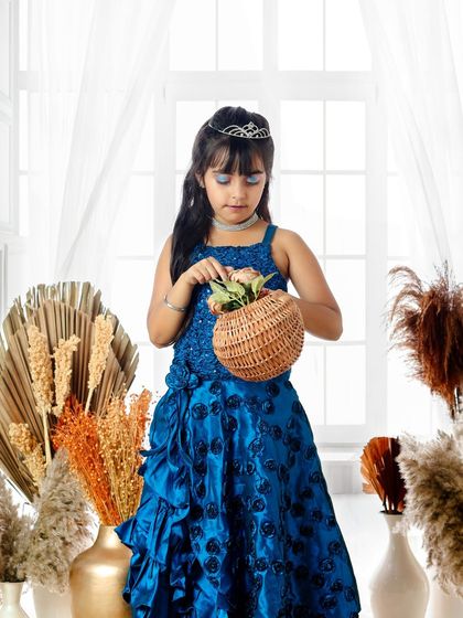 This little princess is tending to her basket of flowers, looking elegant and sweet in her sparkling blue gown and tiara.
