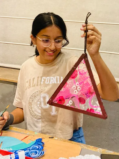 A student smiles as she adds the finishing touches to her pink-themed Diwali lantern.
