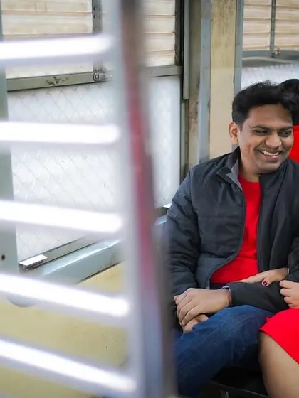 A candid shot capturing the happy conversation between the couple during their unique train-themed pre-wedding shoot. The framing through the window adds a layer of intimacy to the photograph.
