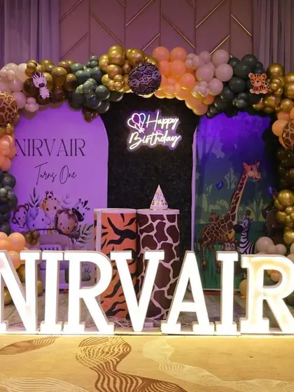 A bold and stylish jungle theme for Nirvair's first birthday. We used a dark backdrop to make the gold, green, and orange balloons pop, complemented by animal print plinths and a "Happy Birthday" neon sign.