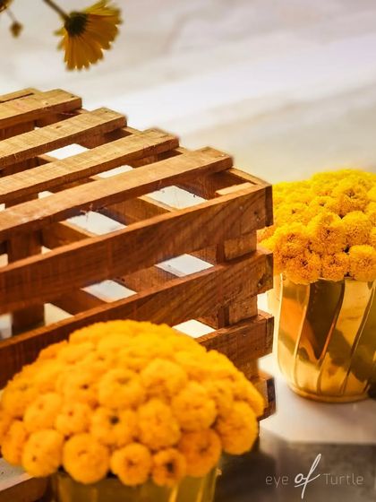 A close-up of the Haldi decor, featuring rustic wooden crates and golden pots filled with bright yellow marigolds.