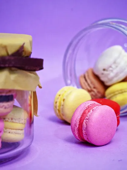 An artistic shot of macarons spilling out of a glass jar, creating a sense of abundance and fun. This type of creative food photography helps a brand stand out.